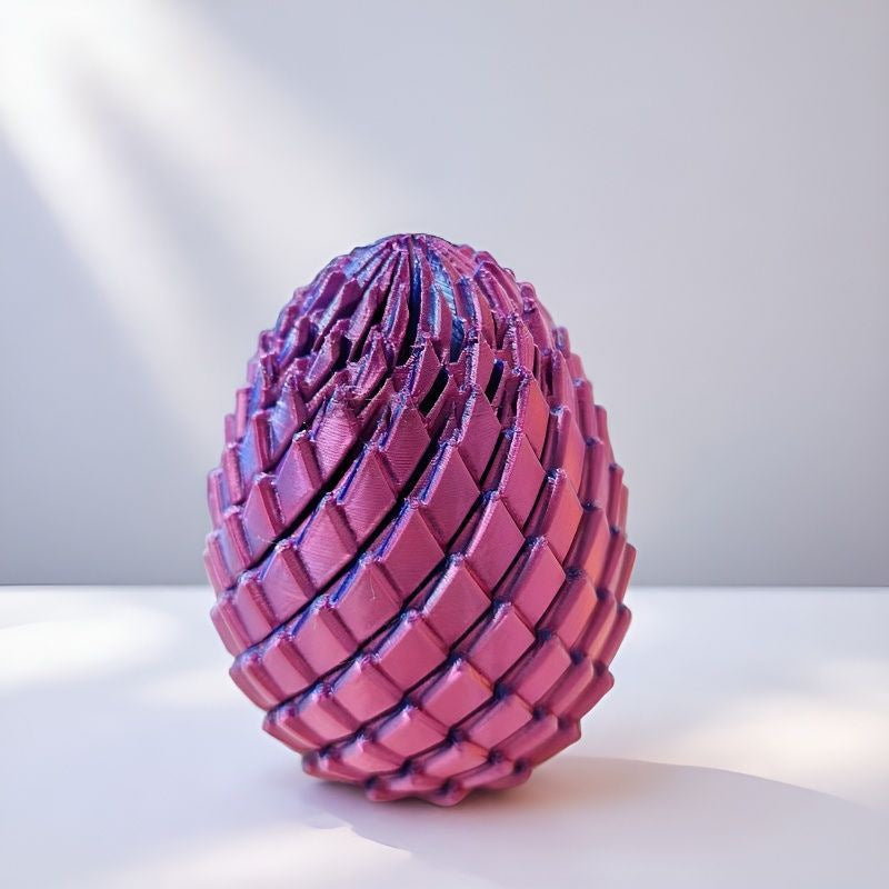 Closed egg with pink and purple scales casting soft shadows on a white surface in bright natural light. 10