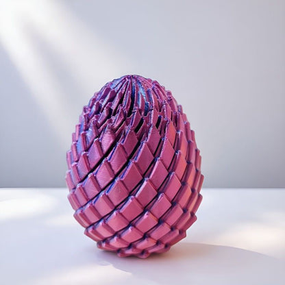 Closed egg with pink and purple scales casting soft shadows on a white surface in bright natural light. 10