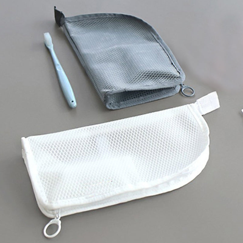Flat lay of a white mesh pouch and a folded grey mesh pouch with zip pull rings, next to a pale blue toothbrush. 6