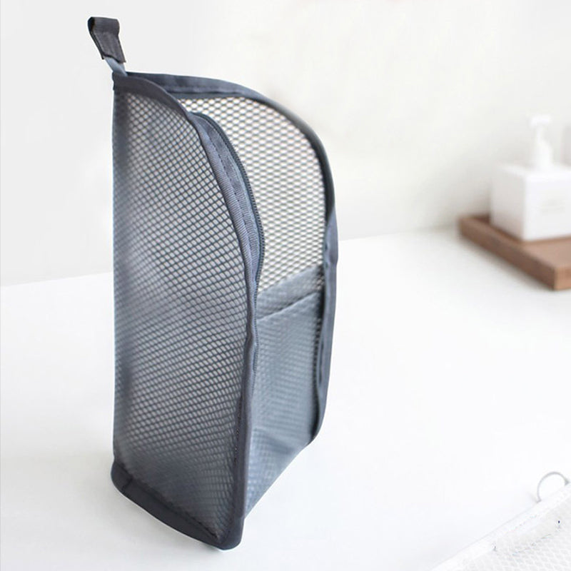 Side view of a grey mesh pouch standing upright on a white surface, showing the curved shape, top loop and front pocket. 7