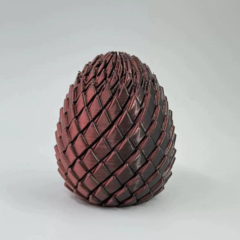 Closed egg with dark red and bronze scales, slightly rough at the top, photographed against a light grey backdrop. 12