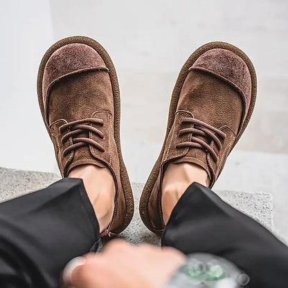 Looking down at a wearer's feet in brown lace-up shoes with suede toe caps and wide, rounded crepe soles. 8