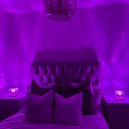 The same bedroom bathed in purple light, with two cube lamps on the bedside tables projecting soft waves up the walls. 3