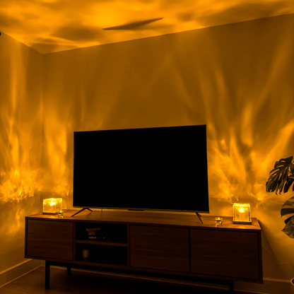 Two glowing cube lamps on a wooden TV unit throw golden flowing light patterns over the walls and ceiling of a living room. 4