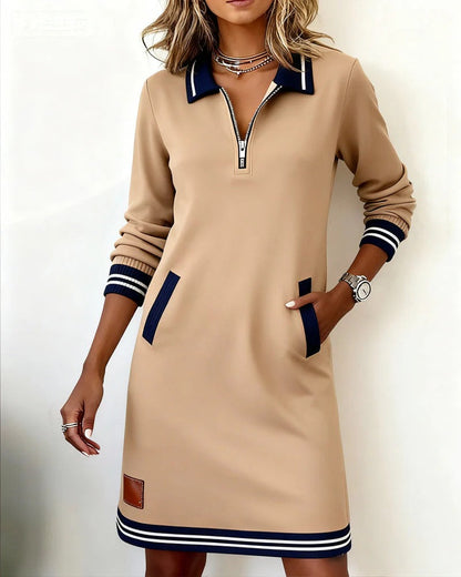 Model wearing the camel-beige version with one hand in a pocket, showing navy pocket trim and striped cuffs and hem. 3