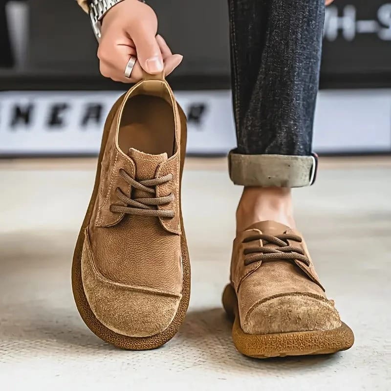 Tan suede lace-up shoes, one held up by the heel tab and one worn with rolled grey jeans. 3
