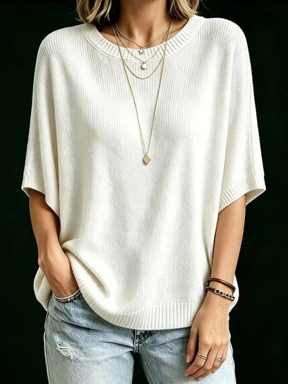Cream knit batwing top worn loosely with one hand in a jeans pocket, showing wide short sleeves and ribbed hem. 24