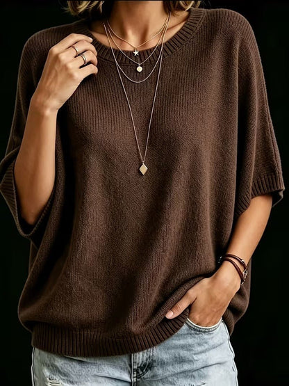 Front view of the dark brown knit top with one hand raised to the shoulder, showing the ribbed round neckline and cuffs. 20