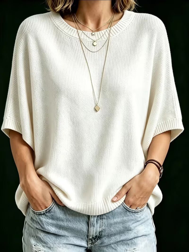 Front view of the cream knit top worn with ripped light jeans, hands in pockets and layered gold necklaces. 23