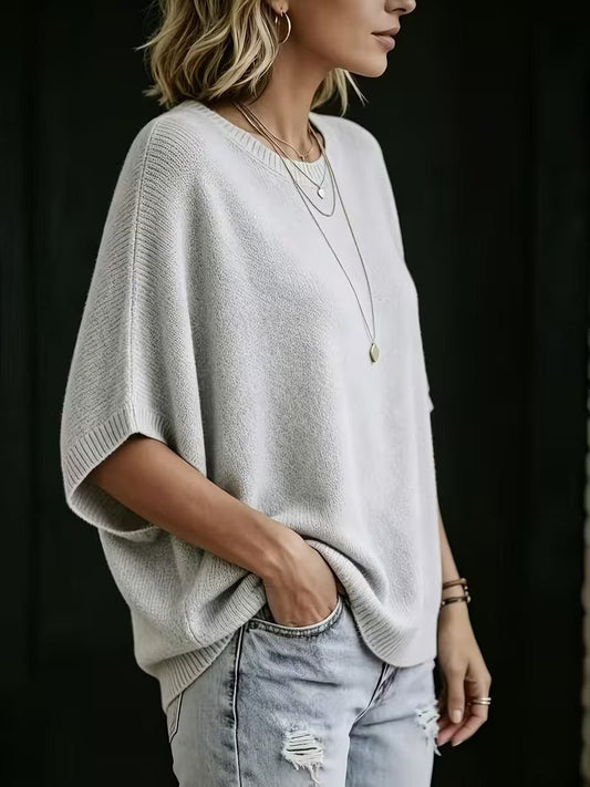 Side view of the light grey knit top worn by a model, showing the wide batwing sleeve and ribbed hem. 2