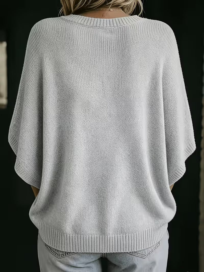 Back view of the light grey knit top on a model, showing the ribbed round neckline, wide sleeves and hem. 3