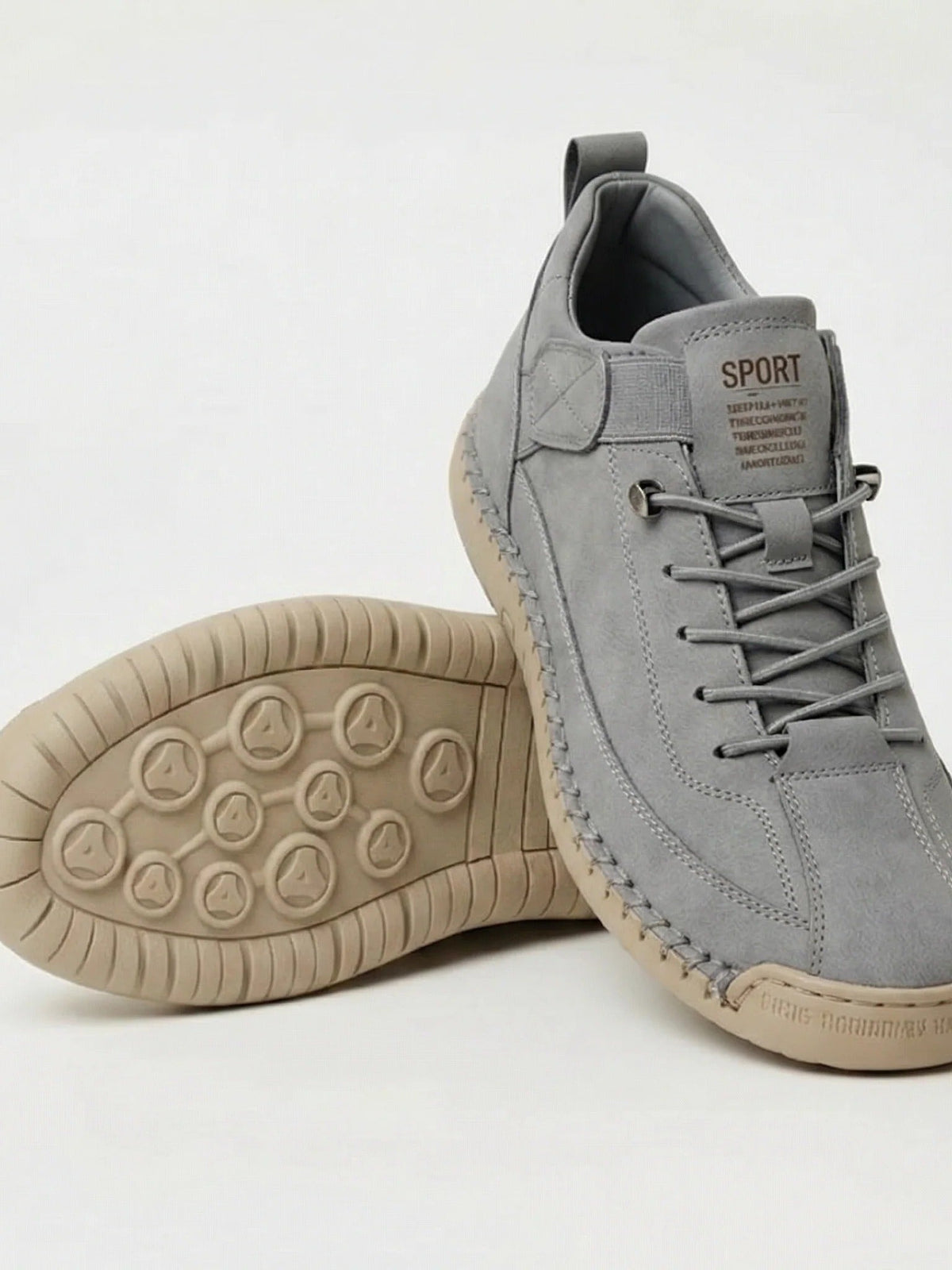Pair of grey suede-look trainers with elastic laces, one propped to show the tan studded sole 17