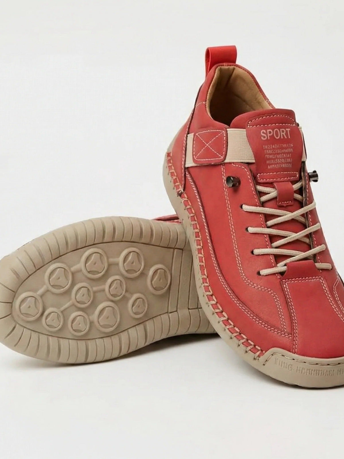 Red trainers with beige elastic laces and stitching, one shoe tilted to show its patterned sole 10