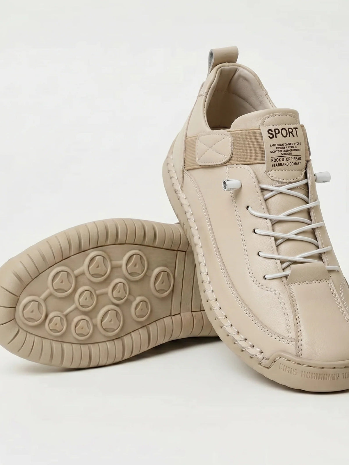 Beige trainers with elastic white laces, one shoe resting on its side to show the patterned rubber sole 12