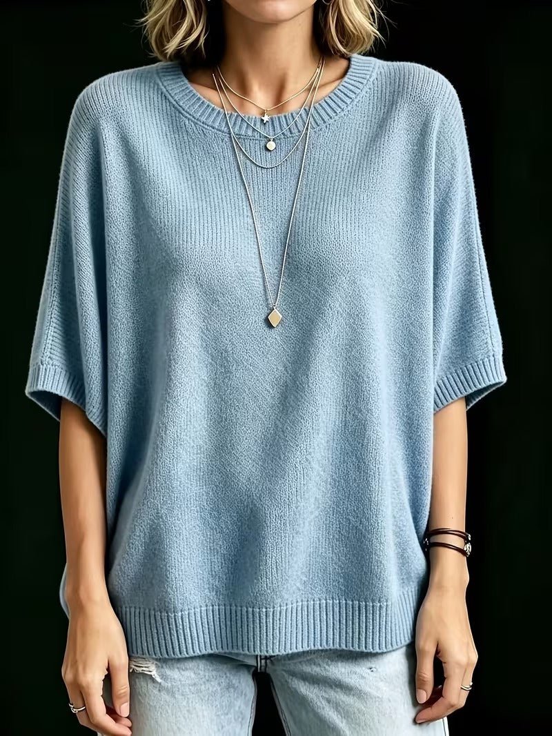 Straight-on front view of the light blue knit top with arms by the sides, showing the ribbed round neck and hem. 16