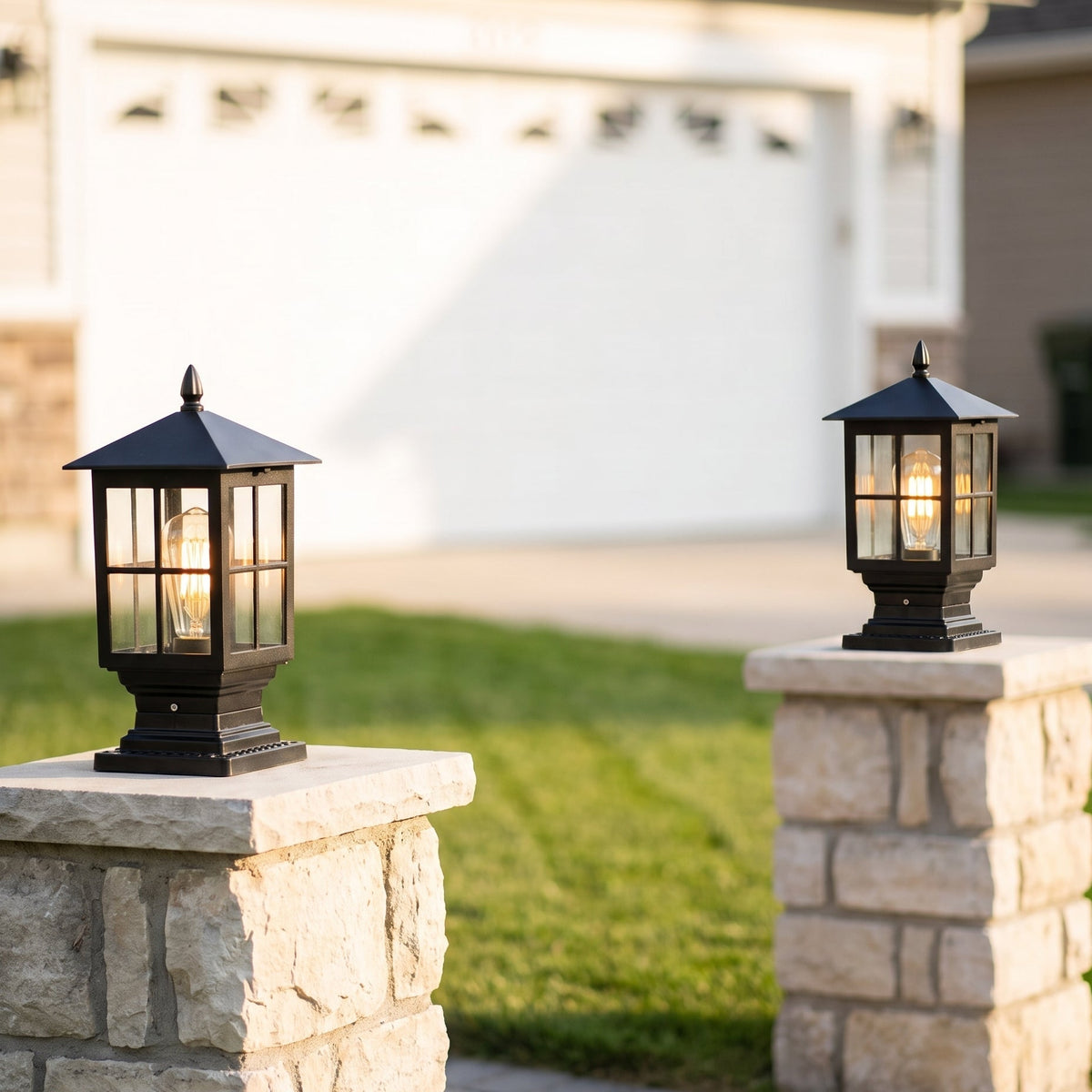 Pair of black pillar lamps with warm glowing bulbs on stone gateposts, lawn and white garage door behind. 8