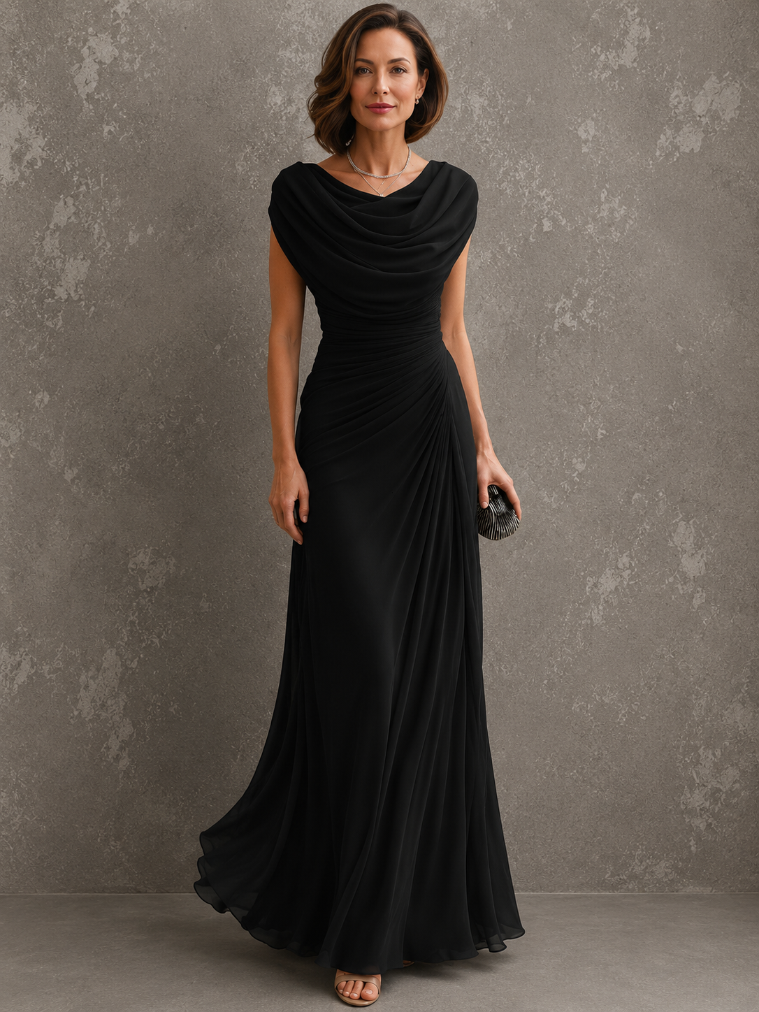 Full-length view of the dress in black, worn by a model, with draped cowl neckline, ruched waist and floor-length skirt. 4