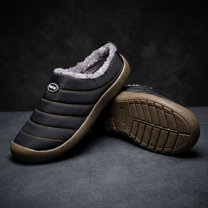Black quilted slipper beside its upturned partner, showing the anti-slip tread pattern on the sole 19