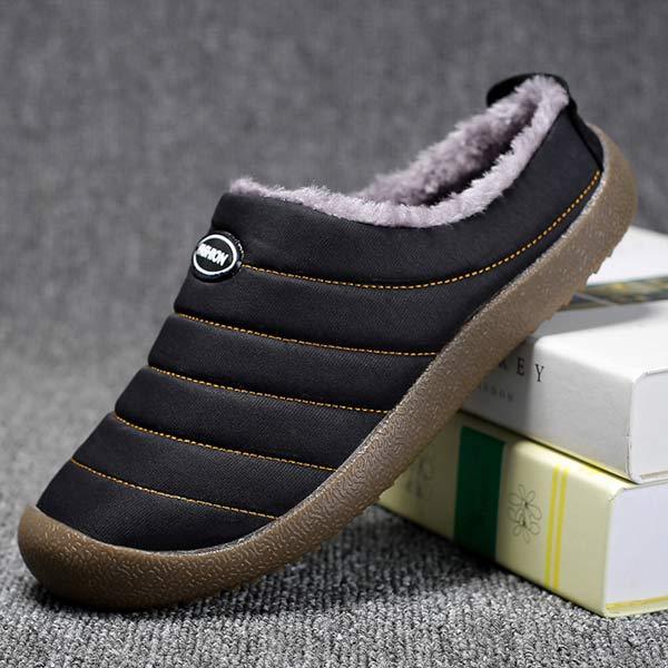 Side profile of a black slipper tilted on books, showing stitched panels and fluffy lining 10
