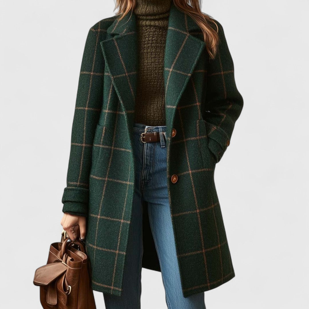 Model wearing the open green checked coat over an olive roll-neck jumper and blue jeans, holding a brown leather bag. 1