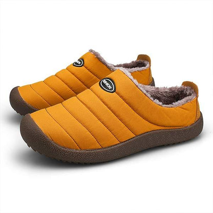 Pair of mustard orange quilted slippers with fleece lining and dark brown soles on white background 11