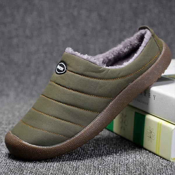 Single olive green slipper tilted against books, showing side stitching and thick brown sole 3