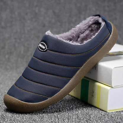 Navy slipper tilted on a pile of books, showing quilted stripes and soft fleece interior 7