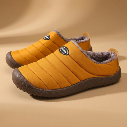 Pair of mustard orange quilted slippers with grey fleece lining on a tan backdrop 20