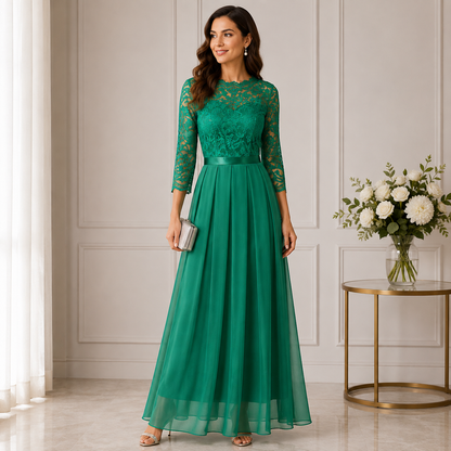 Model in an emerald green maxi dress with lace bodice and sheer pleated skirt, holding a clutch 1