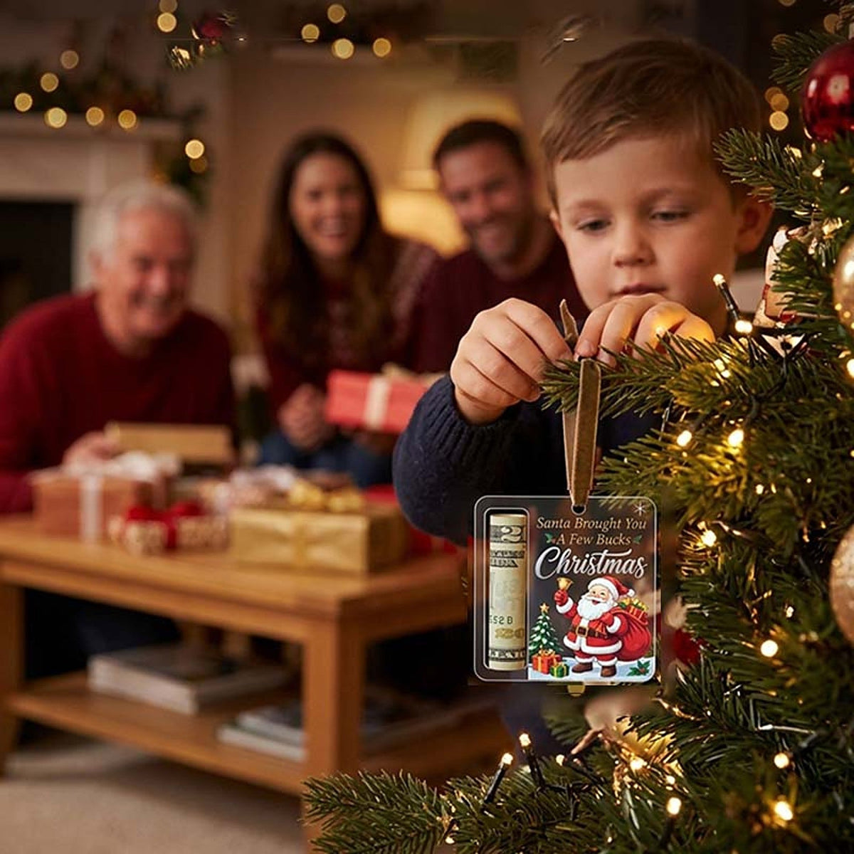 Child hangs the ornament holding a rolled note on a tree branch while family members sit with presents behind. 11