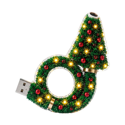 Cut-out of the lamp on a white background, with a green tree and wreath shape, red baubles, warm lights and a USB plug. 1