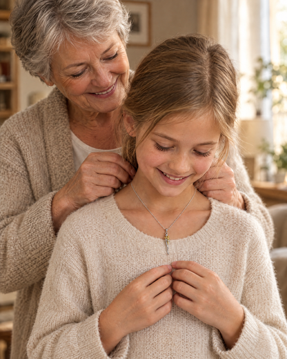 Grandmother fastening the necklace around a smiling young girl's neck, both wearing soft knitted cream tops indoors. 4