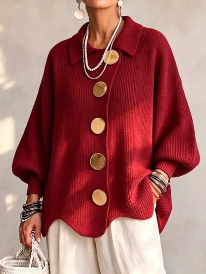 Bright red ribbed cardigan on a model, with gold buttons, balloon sleeves and wavy hem, worn with cream trousers. 11