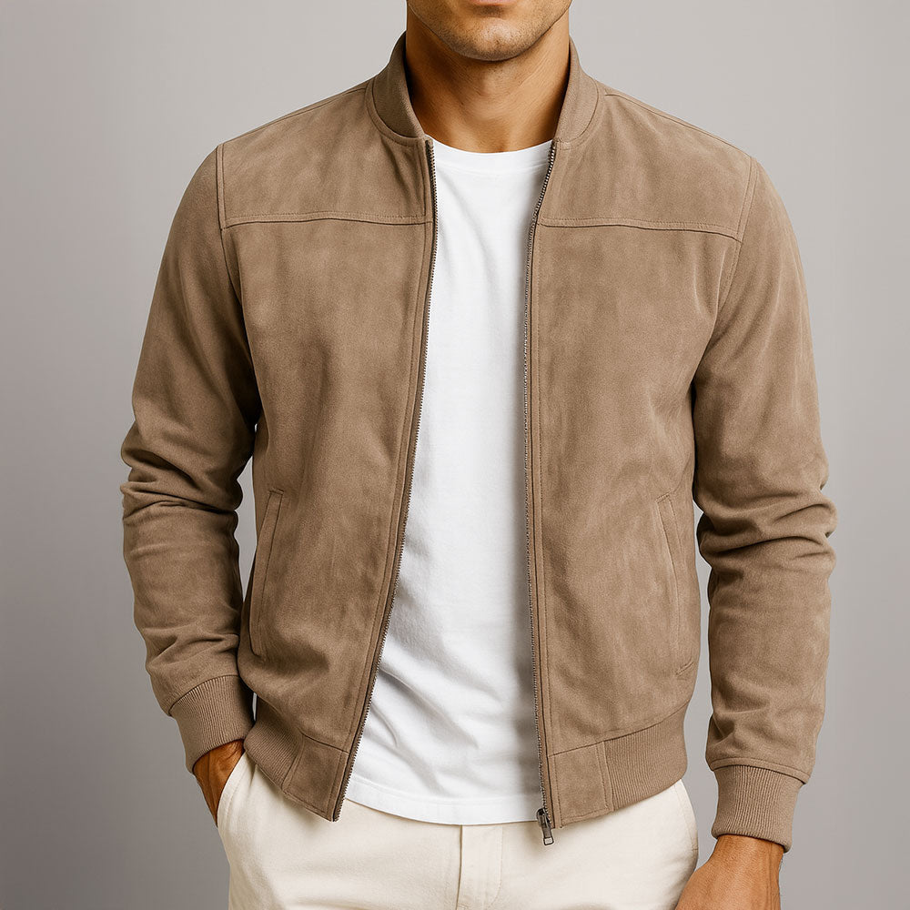 Model wearing the jacket in tan, unzipped over a white t-shirt and cream trousers, with one hand in a pocket. 1