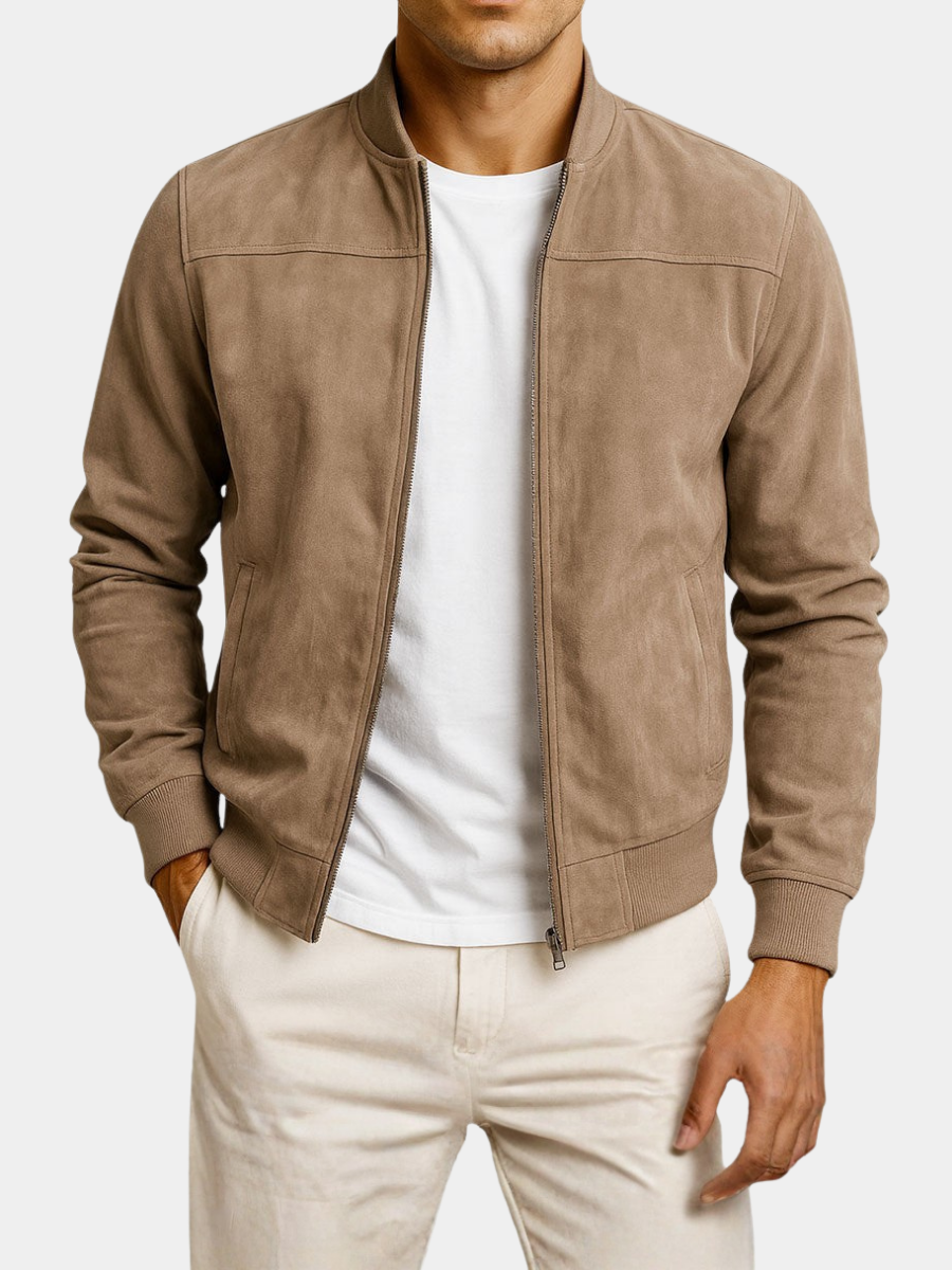 Tan jacket on a plain white background, worn open over a white t-shirt and cream trousers, showing the zip and front pockets. 6