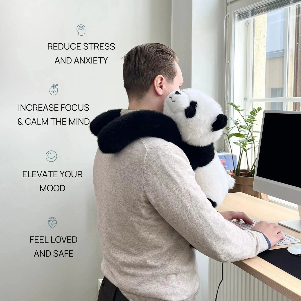 Man in a grey jumper at a standing desk with the panda plush draped over his shoulders, long arms hugging him. 2
