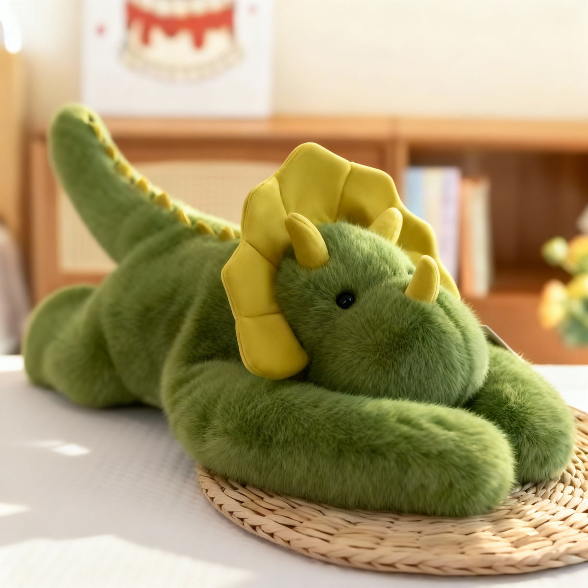 Green dragon plush with a yellow frill and horns, a spiked tail and long arms, lying on a woven straw mat. 15