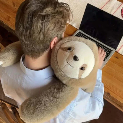 View from above of a man working at a laptop with a sloth plush hugging his neck and shoulders. 9