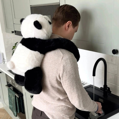 Man standing at a kitchen sink with the panda plush clinging to his back, long arms wrapped around his shoulders. 10