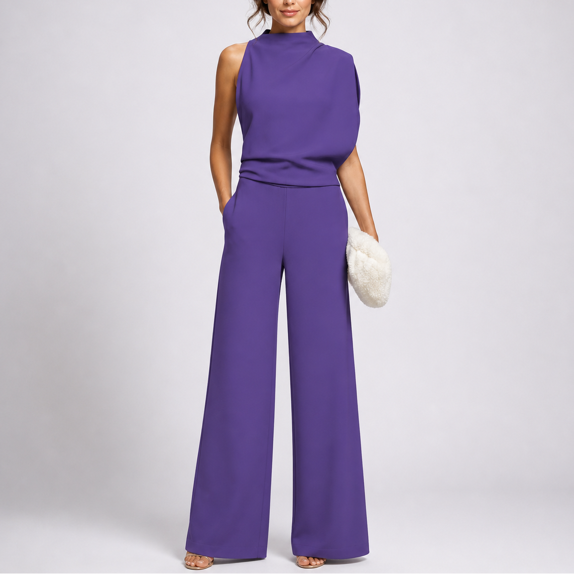 Model wearing the jumpsuit in purple with an asymmetric draped bodice and strappy sandals 3