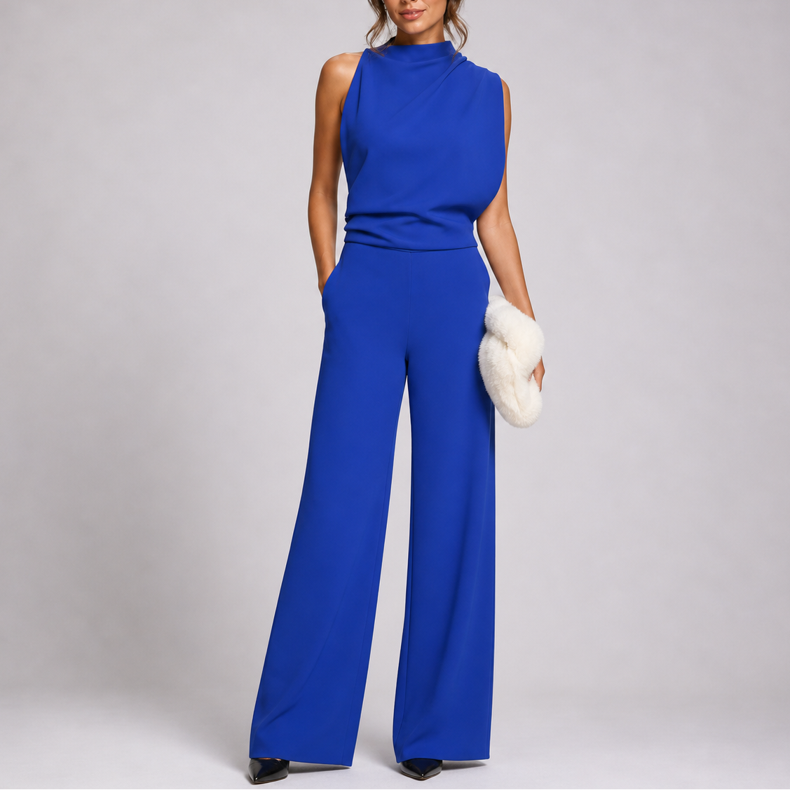 Model wearing the jumpsuit in royal blue with a gathered waist and black pointed heels 6