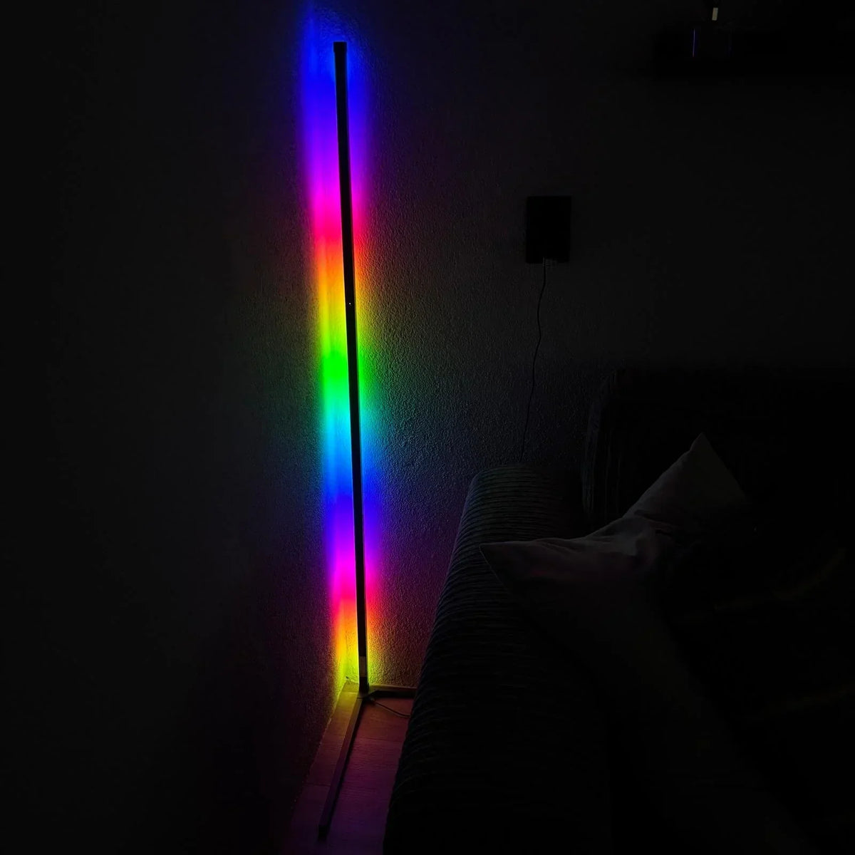 Lamp in a dark room producing a rainbow of colours from blue through green and yellow to pink on the wall. 6