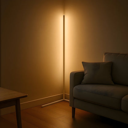 White-framed version of the lamp giving off a warm glow in a corner beside a grey sofa and wooden table. 7