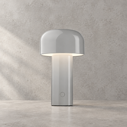 Glossy light grey lamp lit against a textured wall, round touch button visible on the stem 32