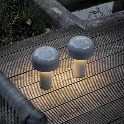 Two grey mushroom-shaped lamps lit on an outdoor wooden decking at dusk 22