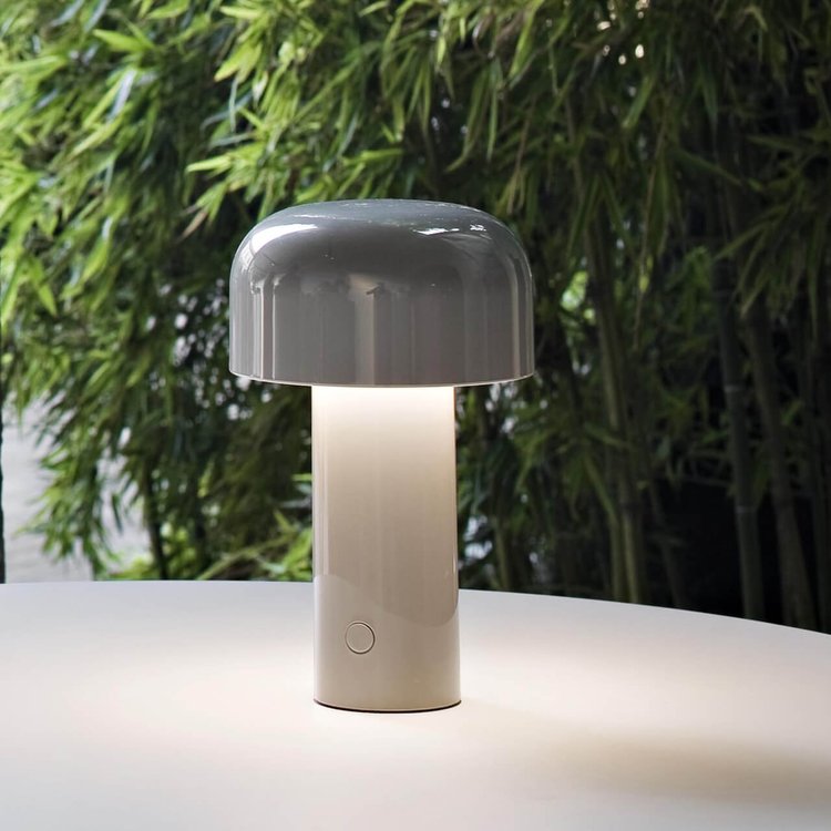 Grey-domed lamp with a pale glowing stem on a white table in front of bamboo 9
