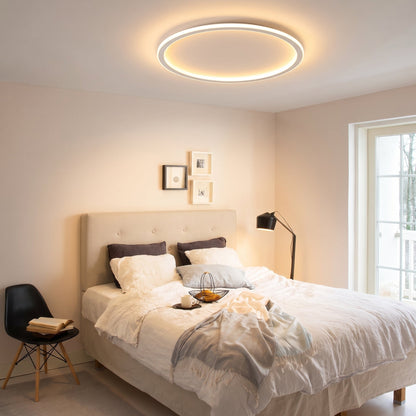 Lit ring ceiling light above a double bed with white linen, a black floor lamp, small framed pictures and a balcony door. 9