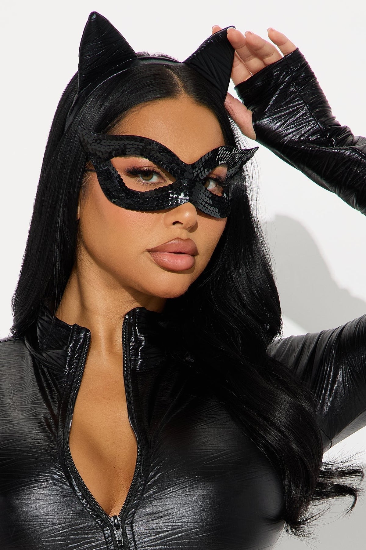 Close-up of the sequinned black eye mask and cat-ear headband, with the model touching one ear 3