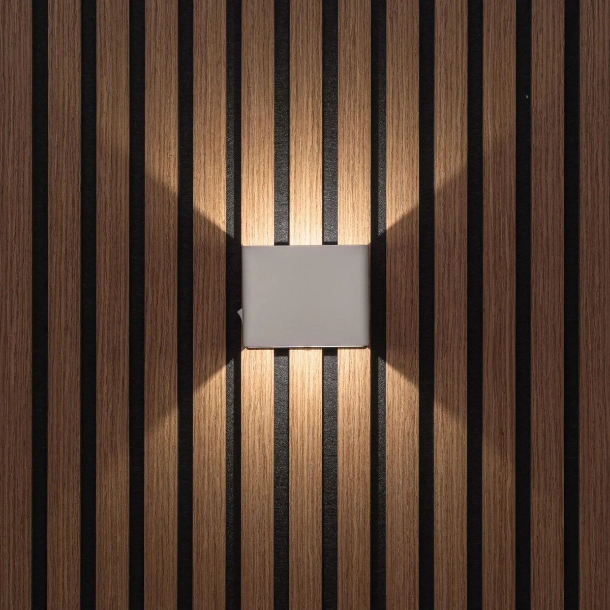 Front view of the light grey cube light casting warm light on a slatted wall 6