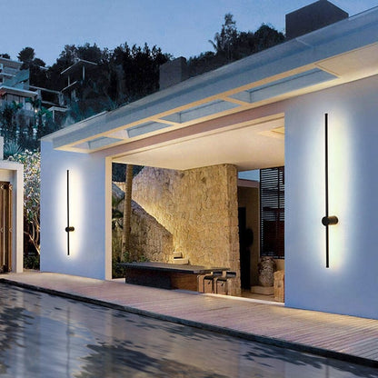 Tall vertical black light bars on either side of an open patio entrance, lit warmly beside a reflective pool at dusk. 3
